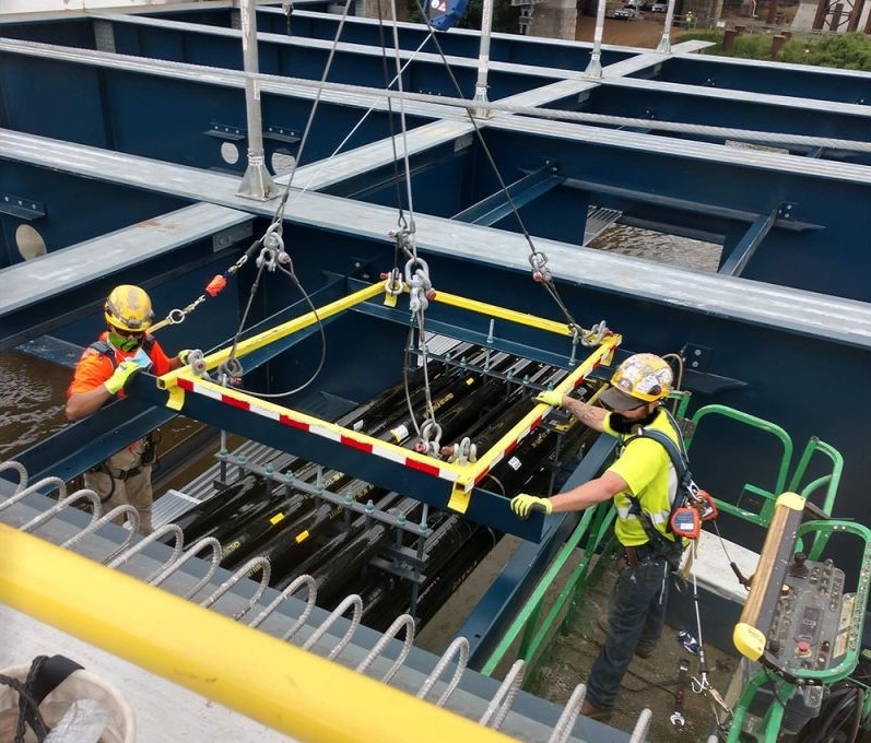 Two installers placing a fiberglass conduit duct bank on the Frederick Douglass Bridge